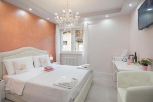 sypialnia z białym łóżkiem i żyrandolem w obiekcie Klemi, rooms in old town Dolomia best home Check in automatico w Trydencie