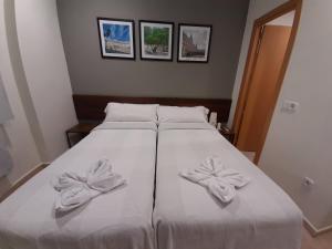 ein Bett mit weißer Bettwäsche und Bögen darauf in der Unterkunft CH Murallas II in Madrid