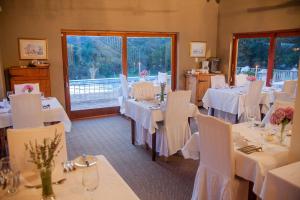 un comedor con mesas blancas y sillas blancas en Steynshoop Mountain Lodge (Hotel), en Hekpoort