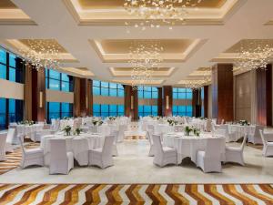 a banquet hall with white tables and chairs and windows at Fairmont Ajman in Ajman  +37 photos