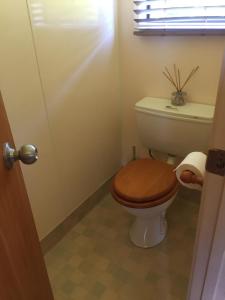 a bathroom with a toilet with a wooden toilet seat at The Bungalow in Great Barrier Island