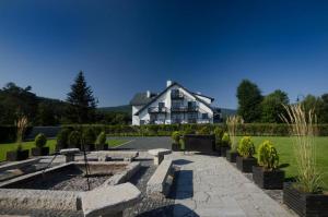 a large white house with a landscaping in front of it at Villa Hotelu Seidorf in Sosnówka