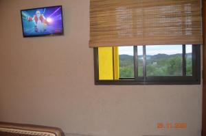 ventana en una habitación con TV en la pared en Posada Tampu Kuntur en San Antonio de Arredondo