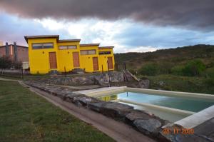uma casa amarela com uma piscina em frente em Posada Tampu Kuntur em San Antonio de Arredondo