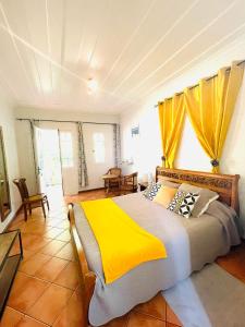 a bedroom with a large bed with a yellow blanket at Relais Des Gouverneurs in Salazie