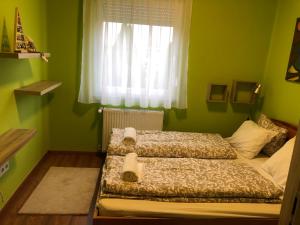 2 camas en un dormitorio verde con ventana en Galéria deluxe apartman, en Mezőkövesd