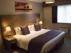 a hotel room with a large bed with purple pillows at The White Hart in Swindon