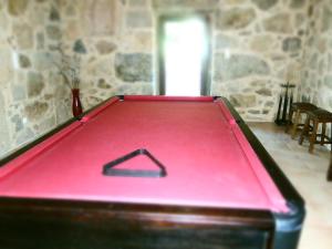 una mesa de billar roja en una habitación con una pared de piedra en Quinta da Gandra, en Paredes de Coura