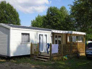 una pequeña casa blanca pequeña con porche en Camping Pen Guen en Saint-Cast-le-Guildo