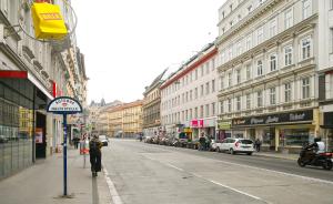 eine Stadtstraße mit Gebäuden und Menschen, die auf der Straße spazieren in der Unterkunft Highlight Apartment St Charles Church in Wien