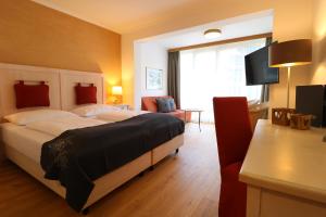 ein Hotelzimmer mit einem Bett und einem TV in der Unterkunft Hotel Bräu in Rauris
