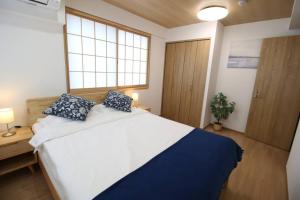 1 dormitorio con 1 cama blanca grande con almohadas azules en Uhome Suido Apartment SD, en Tokio
