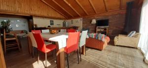 a dining room with a table and red chairs at Casa Amanecer Vichuquén in Lago Vichuquen