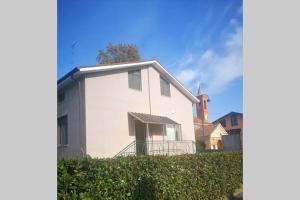 a white house with a church in the background at "La ca` 'd Giaculin" -Casetta indipendente in Magliano Alpi