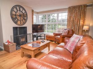 a living room with a leather couch and a fireplace at Plumblands in Ambleside