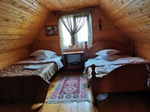 two beds in a wooden room with a window at Casa Vladut in Babadau