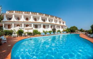 a hotel with a large swimming pool in front of a building at Hotel Punta Est in Baja Sardinia