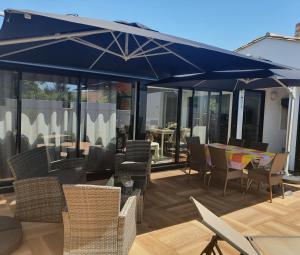 un patio con ombrellone, sedie e tavoli blu di Appartement le Pas Sage du Marché La Flotte a La Flotte