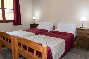 1 dormitorio con 2 camas, 2 mesas y una ventana en Cabañas "Las Escondidas" en Valle Grande