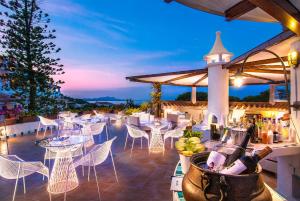 un restaurante con mesas y sillas blancas y una puesta de sol en Hotel Punta Est, en Baja Sardinia