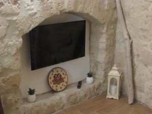 a stone wall with a tv and a clock and a lantern at Loft Albicocca in Bari