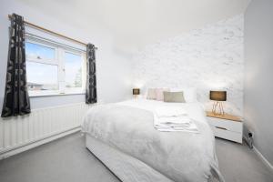 a white bedroom with a large bed and a window at Pendicke Cottage, Southam in Southam