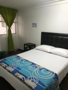 um quarto com uma cama com um cobertor azul e branco em Hostal El Eden Manizales em Manizales