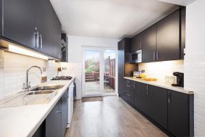 a kitchen with black cabinets and a sink at Pendicke Cottage, Southam in Southam