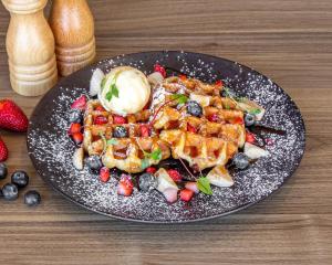 a plate of food with waffles and fruit on a table at Quest Bella Vista in Baulkham Hills