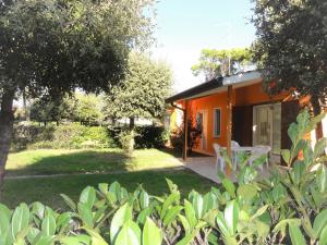 una casa arancione con prato e alberi di Villa Dogi Sud 20 a Bibione