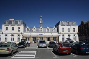 un estacionamiento con autos estacionados frente a un edificio en Villa Normande, en Le Tréport