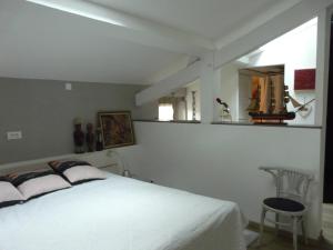a bedroom with a white bed and a chair at gites Les Lebes - Grange loft in Sempesserre