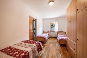 three beds in a room with wooden floors at Villa Mazzel - Cima 12 in Vigo di Fassa