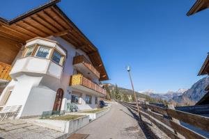 a building on a street with mountains in the background at Villa Mazzel - Cima 12 in Vigo di Fassa