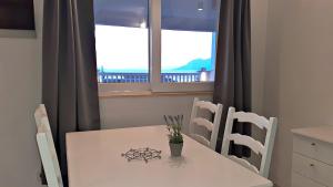 Biały stół i krzesła z oknem w obiekcie Apartments Villa Bonaca w Baskiej Vodzie