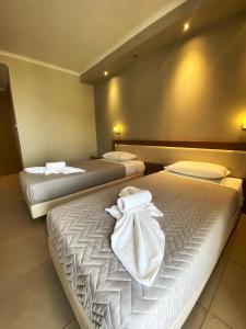 two beds in a room with white towels on them at Cosmos Hotel in Vasiliki