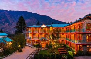 a large building with a mountain in the background at Zen Manali by Keekoo Stays in Manāli