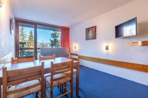 Un comedor con mesa y sillas y una ventana. en LES ARCS 1800 Village du Charvet, en Bourg-Saint-Maurice