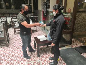 Una mujer con una máscara facial y un hombre estrechando la mano en Hotel de los baños, en Pachuca de Soto