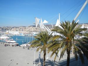 a beach with palm trees and a harbor with boats at Hotel La Superba in Genoa