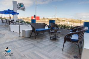 eine Terrasse mit Stühlen, Tischen und einem Sonnenschirm in der Unterkunft Pousada Ilha dos Lobos in Torres