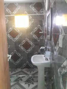 a bathroom with a sink and a tiled wall at Las Hermanas in Las Grutas