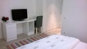 Schlafzimmer mit einem Schreibtisch, einem TV und einem Bett in der Unterkunft Hotel Baleal Spot in Baleal