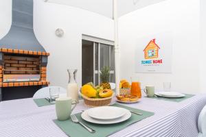 un tavolo con piatti bianchi e frutta di TOMÁS HOME a Nazaré