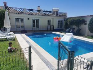 a house with a swimming pool with a child in it at Férias Inesquecíveis in Carregado