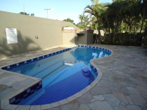 a swimming pool with blue tile in a backyard at Apartamento em Boracéia no Litoral Norte in Bertioga