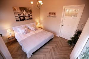 a bedroom with a large white bed with a chandelier at B&B Oldemarkt in Oldemarkt