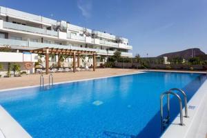 a large blue swimming pool in front of a building at Tejita beach , The beach dream flats in Granadilla de Abona