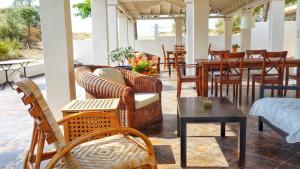 a patio with wicker chairs and tables and a table at Olive Bay Hilltop Apartments Ammouliani in Ammouliani
