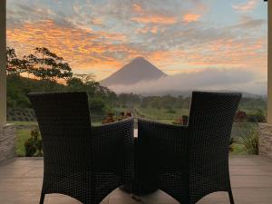 two chairs sitting on a patio with a view of a mountain at Arenal Roca Suites in Fortuna
